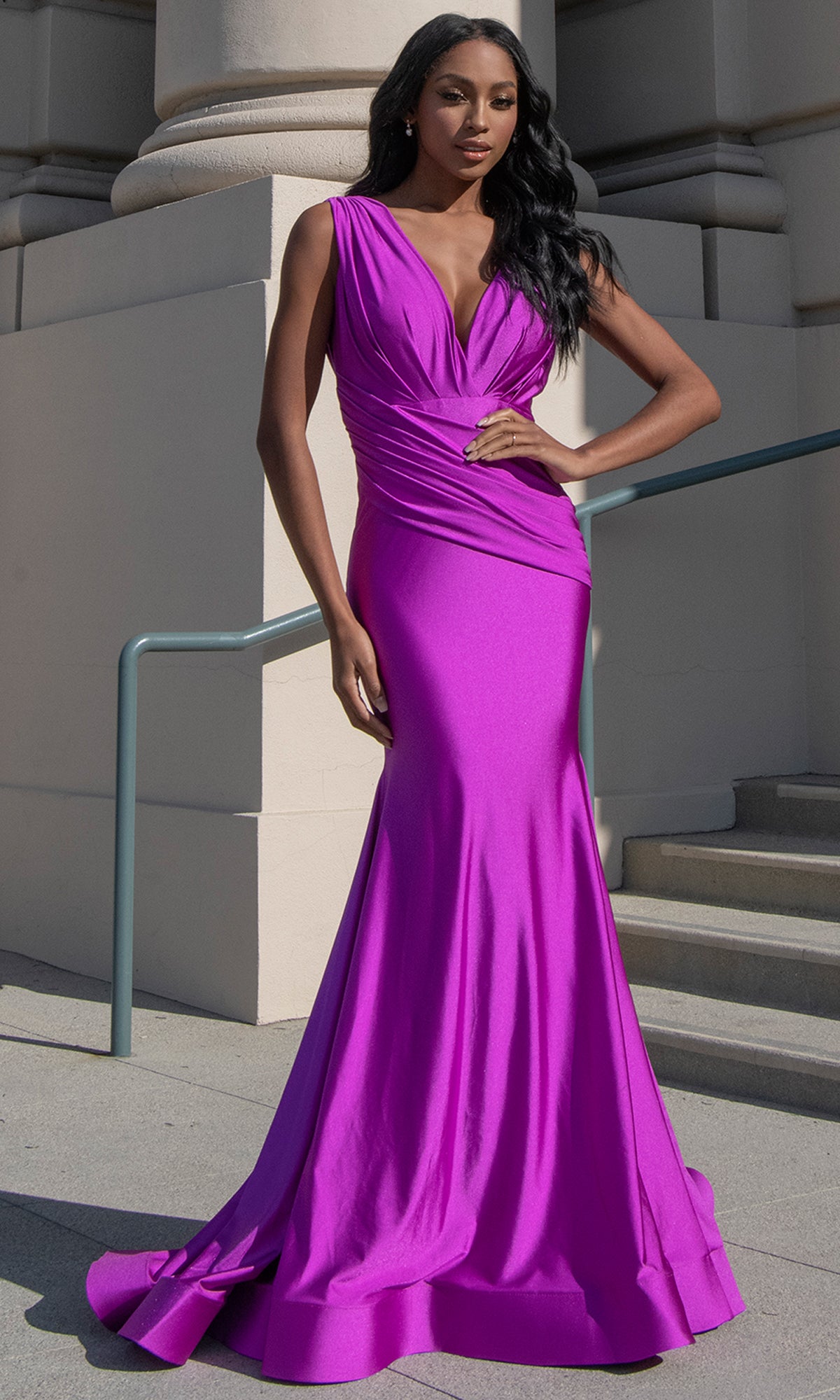 A woman stands on outdoor steps wearing the Sash-Waist Long Mermaid Prom Dress: Amelia 370-1, a magenta sleeveless gown with a fitted bodice and elegant draped detailing.
